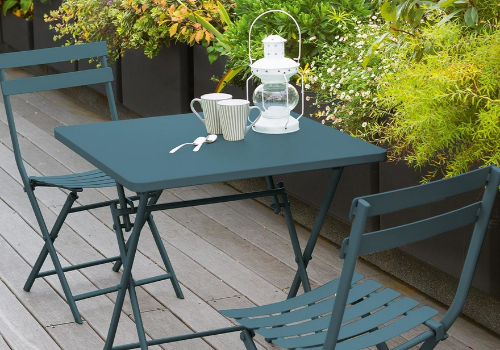 Une petite table pliante et ses deux chaises pliantes sur un balcon fleuri